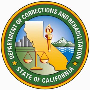 Seal of the California Department of Corrections and Rehabilitation, featuring a gold California map, a torch, scales of justice, cityscape, mountains, and ocean, with green and gold circular border text.