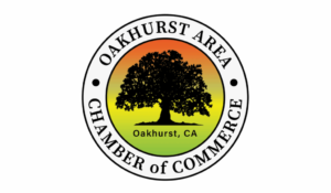Logo showing a black tree silhouette on a yellow-green gradient background, with text reading Oakhurst Area Chamber of Commerce and Oakhurst, CA inside a circular border.